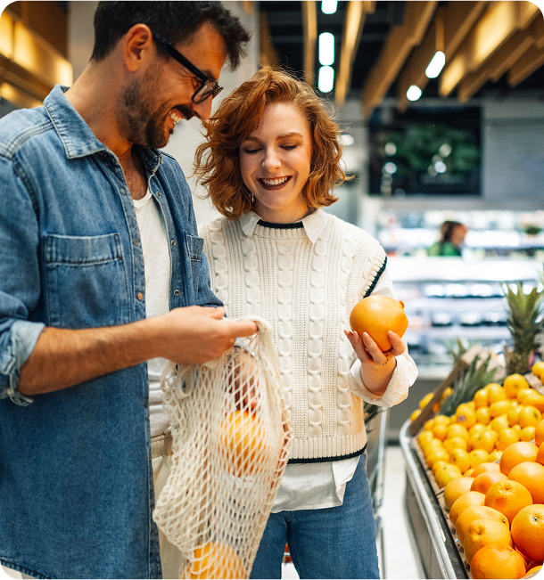 Couple shopping for oranges at supermarket.